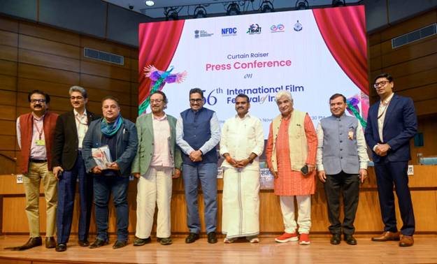 A group of ten men, some in traditional Indian attire and some in suits, stand on a stage in front of a large screen displaying the "6th International Film Festival" logo.