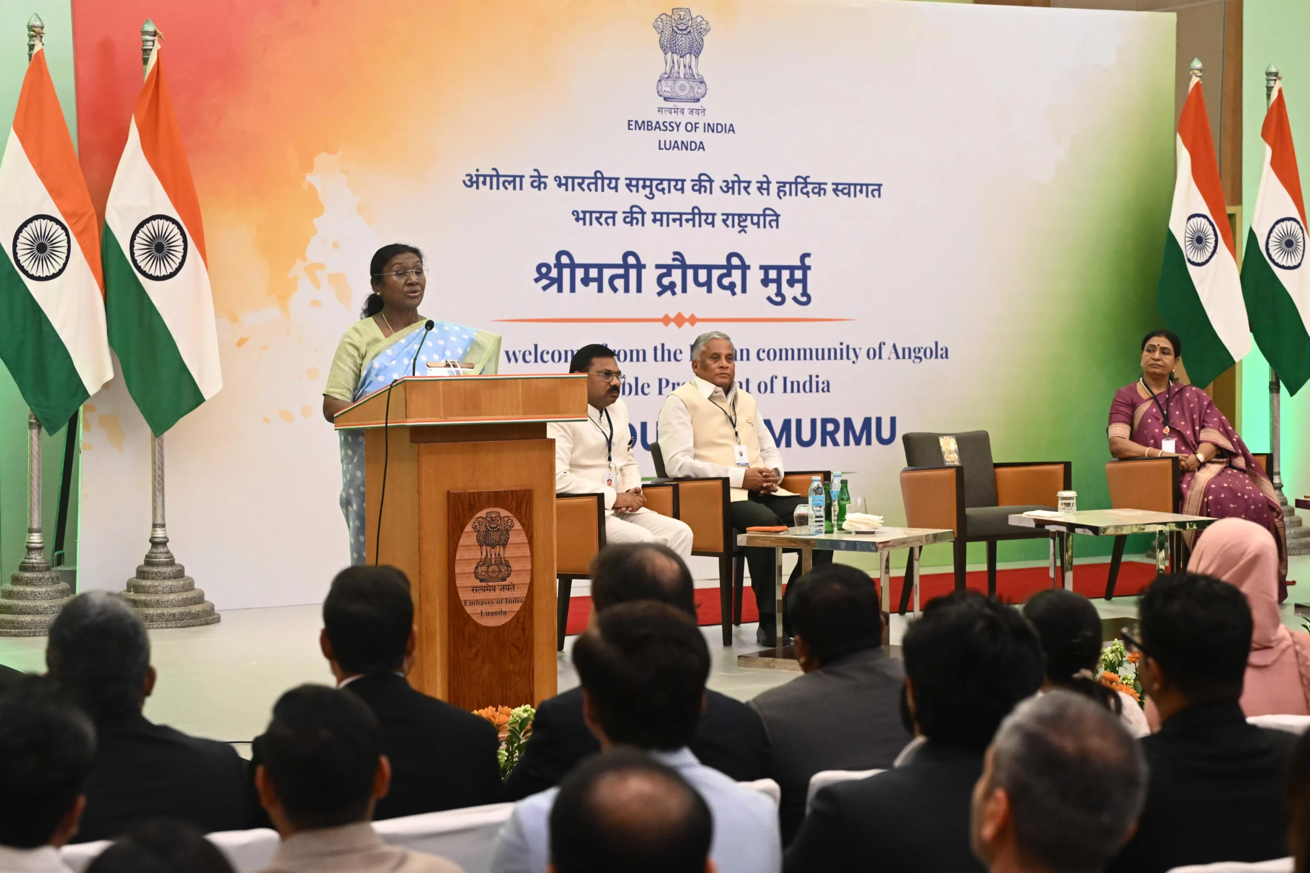 President of India Droupadi Murmu speaking at a podium during an interaction with the Indian community at an event hosted by the Embassy of India in Luanda, Angola.