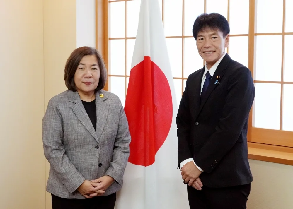 Philippine Ambassador to Japan Mylene J. Garcia-Albano and Japan's Vice Minister of Finance for International Affairs Masato Kanda stand in front of a Japanese flag.