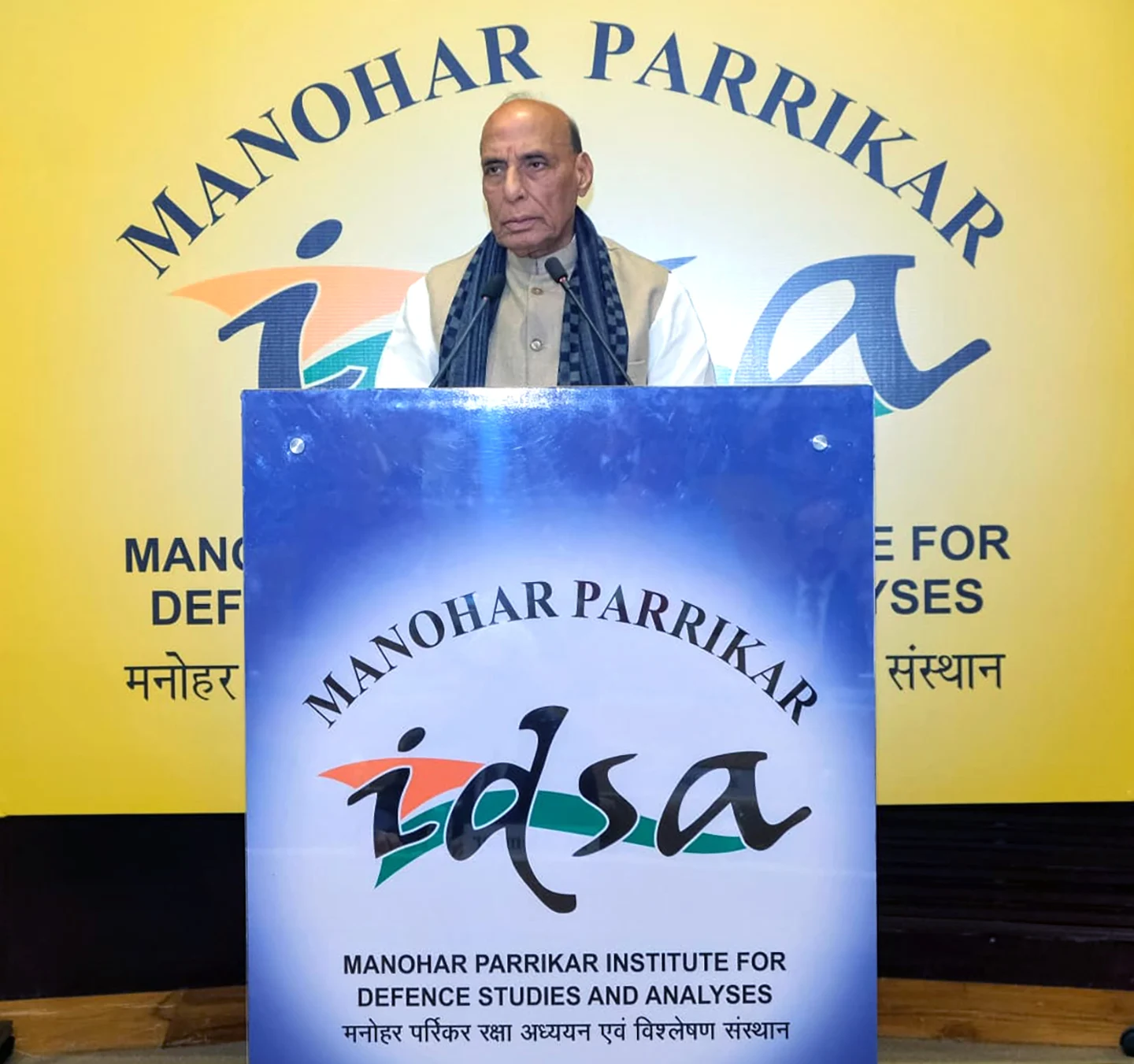 Rajnath Singh speaking at a podium with "MANOHAR PARRIKAR idsa" logo in the background and on the podium.