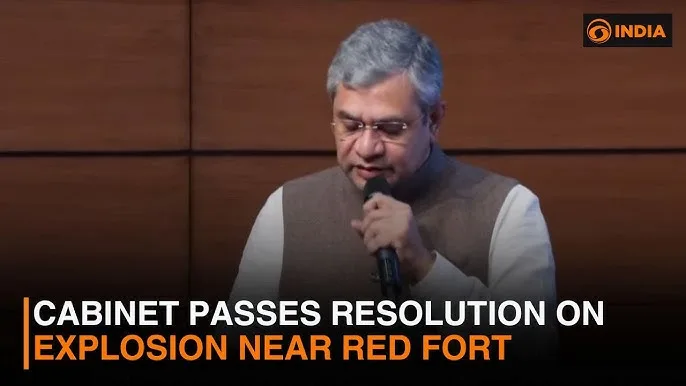 A man in glasses and a vest speaking into a microphone with text on the screen that reads "CABINET PASSES RESOLUTION ON EXPLOSION NEAR RED FORT."