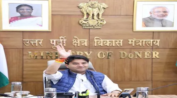 Jyotiraditya Scindia, Union Minister for Civil Aviation and Steel, seated at his desk in the Ministry of DoNER office, waving, with portraits of the President and Prime Minister of India in the background.