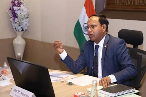 An Indian official, Shri M. Nagaraju, seated at a desk, gestures while speaking during a virtual meeting, with the Indian flag visible in the background.