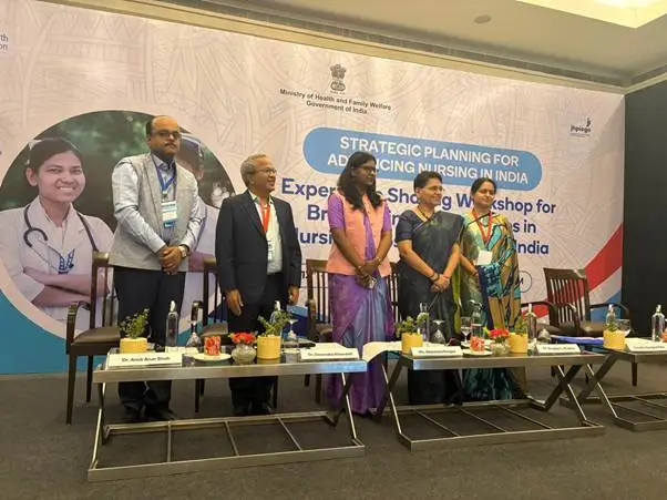 Group of officials and healthcare professionals standing on a stage in front of a banner at the "Strategic Planning for Advancing Nursing in India" event.