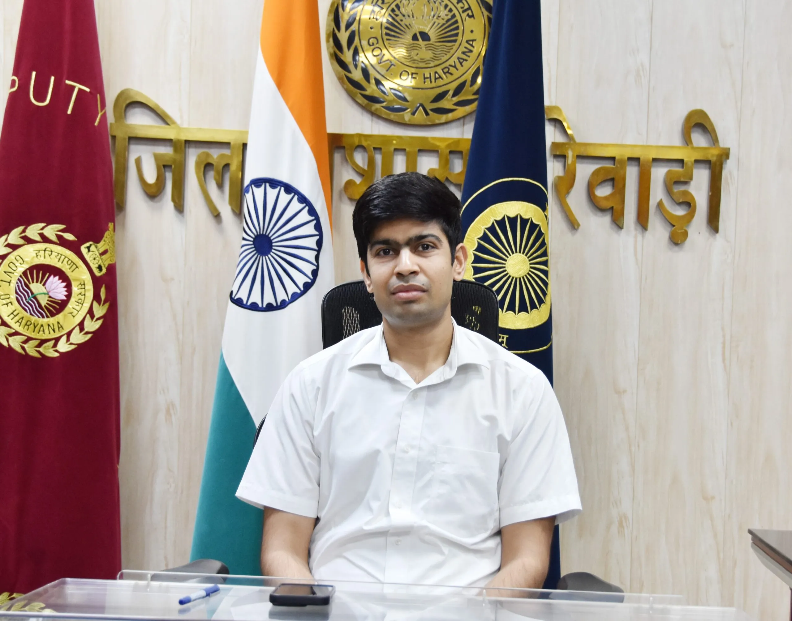 रेवाड़ी के जिलाधीश अभिषेक मीणा अपने कार्यालय में बैठे हैं। पृष्ठभूमि में 'जिला रेवाड़ी' लिखा हुआ है, साथ ही भारतीय राष्ट्रीय ध्वज और हरियाणा सरकार के प्रतीक चिन्ह प्रदर्शित हैं।
