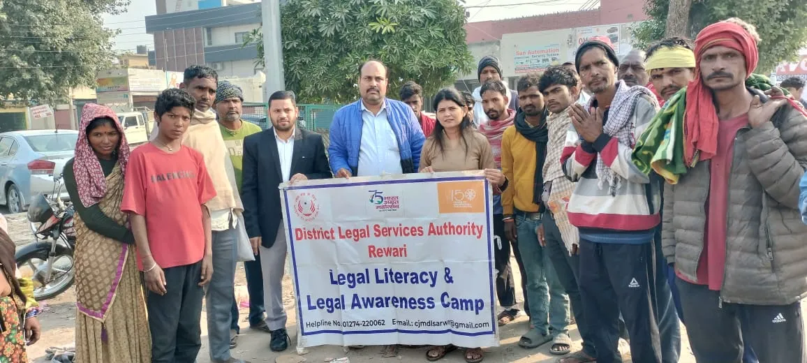 रेवाड़ी के आजाद चौक पर जिला विधिक सेवा प्राधिकरण (DLSA) द्वारा आयोजित 'विधिक साक्षरता और विधिक जागरूकता कैंप' के बैनर के साथ एडवोकेट और पैरा लीगल वालंटियर श्रमिकों को संबोधित करते हुए खड़े हैं।