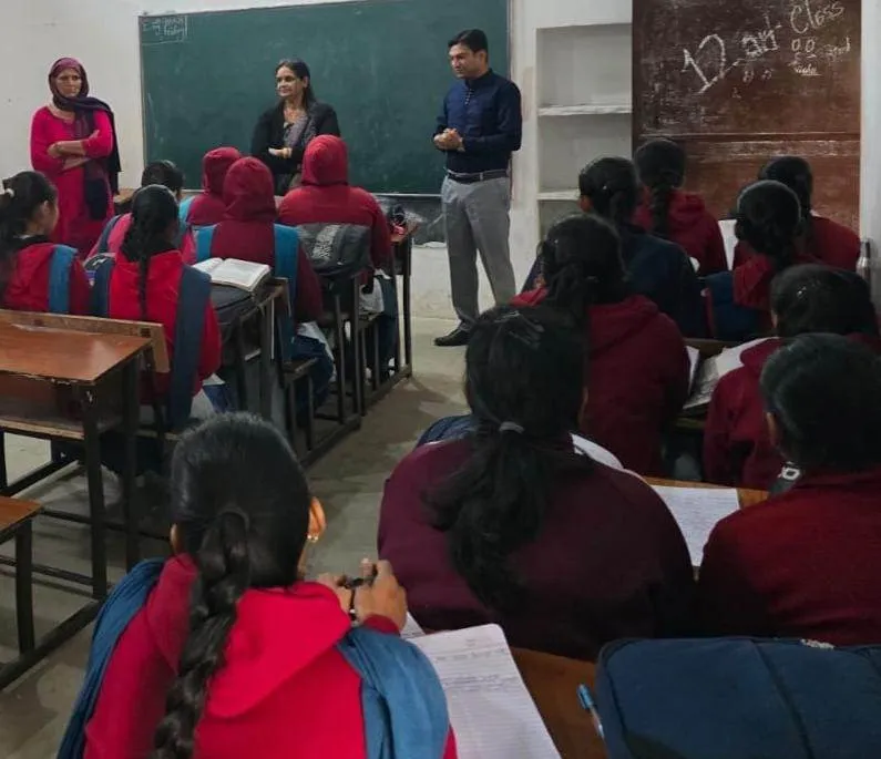 पीएम श्री राजकीय वरिष्ठ माध्यमिक विद्यालय, पाल्हावास की कक्षा में जिला सूचना एवं जनसंपर्क अधिकारी (DIPRO) दिनेश कुमार छात्राओं को संबोधित करते हुए। उनके साथ दो महिला शिक्षक खड़ी हैं, और छात्राएं कक्षा में बैठी हैं।
