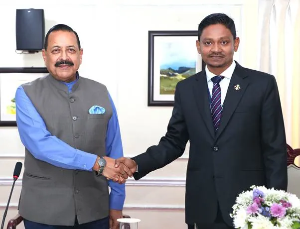 Dr. Jitendra Singh, Union Minister, shaking hands with Shri Yumnam Surchandra Singh during a meeting in an office setting. Dr. Singh is wearing a blue shirt and a grey waistcoat, while Shri Surchandra Singh is in a dark suit with a striped tie.
