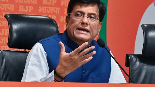 Piyush Goyal, India's Union Minister of Commerce and Industry, addresses a press conference, gesturing with his right hand while speaking into microphones with the BJP logo visible in the background.