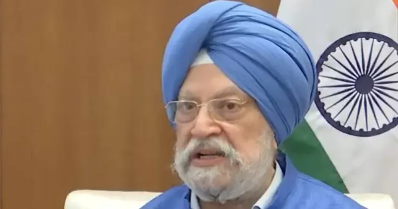 Hardeep Singh Puri, Minister of Petroleum and Natural Gas, wearing a blue turban and glasses, speaking at a podium with an Indian flag visible in the background.