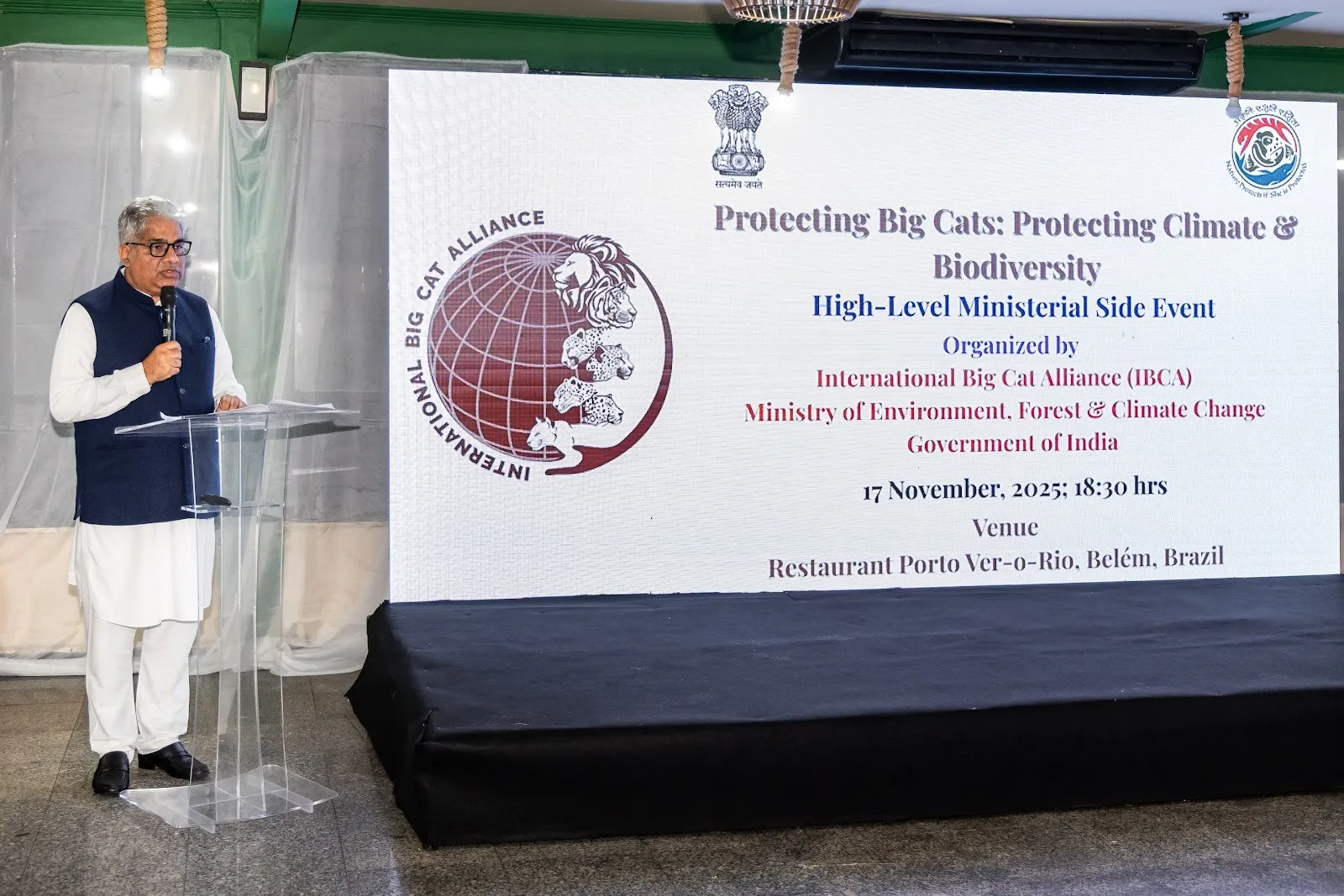 Union Environment Minister Shri Bhupender Yadav speaks at a podium in front of a large screen displaying the 'Protecting Big Cats: Protecting Climate & Biodiversity' event title and the International Big Cat Alliance logo at CoP30 in Belém, Brazil.