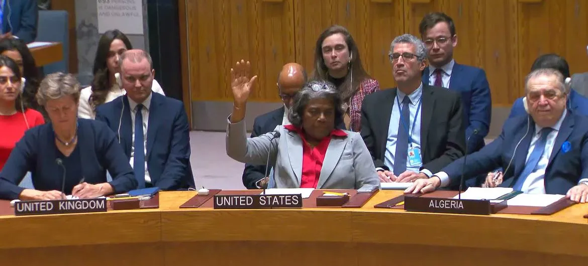 Linda Thomas-Greenfield, U.S. Ambassador to the United Nations, raises her hand to vote during a UN Security Council meeting. She is seated at a table labeled 'UNITED STATES', with representatives from the United Kingdom and Algeria also visible at adjacent tables. Other individuals are seated in the background.