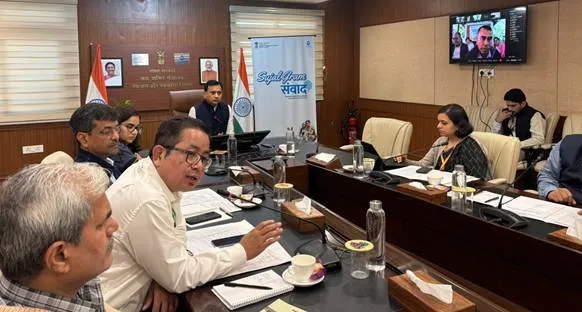 DDWS Secretary Shri Ashok K.K. Meena chairs the inaugural Sujal Gram Samvad meeting at a conference table, with a video conference screen showing remote participants and a banner reading 'Sujal Gram Samvad' in the background.
