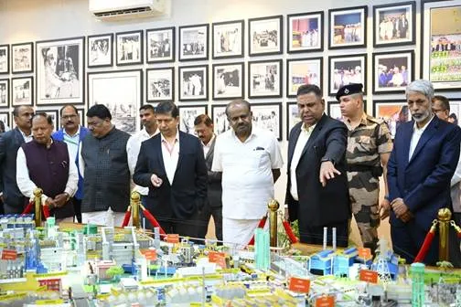 Union Minister H.D. Kumaraswamy and officials standing around a detailed scale model of the Rourkela Steel Plant inside a room with framed historical photos on the wall.