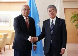 Late Micronesian Foreign Secretary Lorin S. Robert shaking hands with Japanese Foreign Minister Toshimitsu Motegi in front of their national flags during a past bilateral meeting.