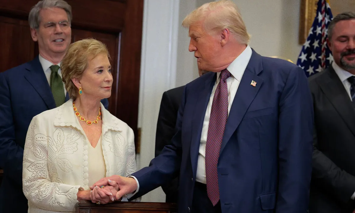 Donald Trump shakes hands with Linda McMahon in a formal office setting while two officials stand in the background smiling.