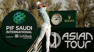  A professional golfer executes a follow-through swing at the PIF Saudi International, with prominent signage displaying the event logo, Rolex clock, and Asian Tour branding in the background.