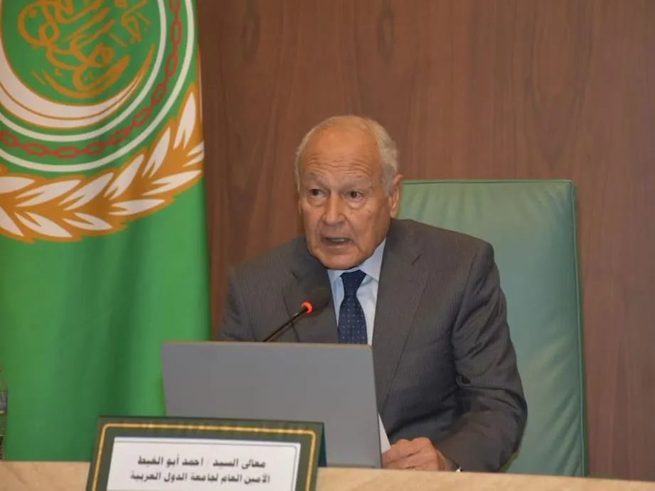 Secretary-General Ahmed Aboul Gheit seated at a desk with the Arab League flag in the background during a press briefing.