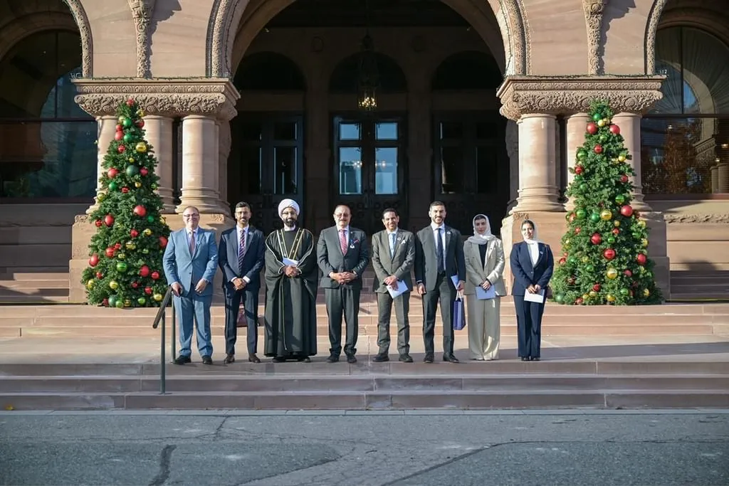 Delegation from TRENDS Research & Advisory and the Global Imams Council standing on the steps of the Legislative Assembly of Ontario flanked by decorated Christmas trees.
