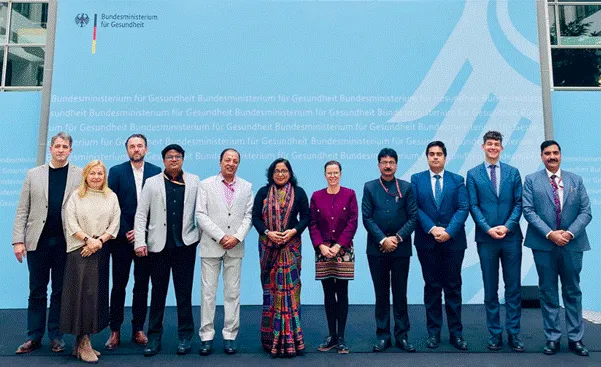 Delegates from India's Ministry of Ayush and Germany's Federal Ministry of Health pose for a group photograph against a blue backdrop featuring the German Health Ministry logo during the 3rd Joint Working Group Meeting in Berlin.