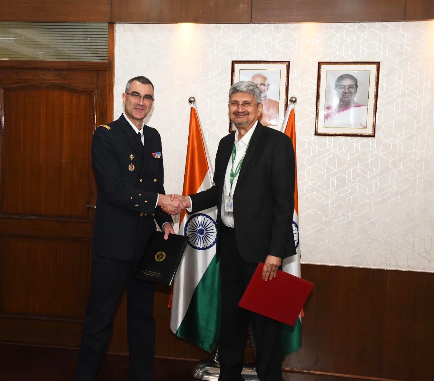 Chairman DRDO Dr Samir V Kamat and Lt Gen Gael Diaz de Tuesta of DGA France shake hands after signing a technical agreement in front of Indian and French flags at DRDO Bhawan.