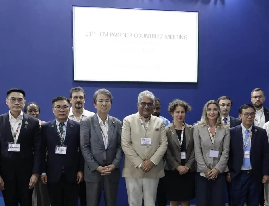 Union Minister Bhupender Yadav and Japanese Minister Hirotaka Ishihara pose with delegates on stage under a screen reading 11th JCM Partner Countries' Meeting at CoP30 in Belém, Brazil.