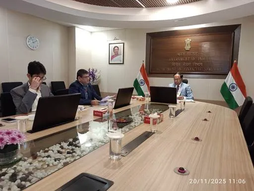 Secretary of Department of Financial Services Shri M. Nagaraju chairing a meeting at a conference table with Indian flags and the Government of India emblem in the background.