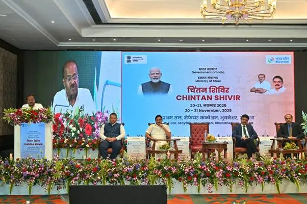 Union Minister H.D. Kumaraswamy addresses the audience from a podium during the Ministry of Steel's Chintan Shivir in Bhubaneswar, while Minister of State Bhupathiraju Srinivasa Varma and other officials sit on stage against a digital backdrop displaying event details and Prime Minister Narendra Modi's image.
