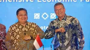 Indonesian Coordinating Minister for Economic Affairs Airlangga Hartarto and EU Executive Vice President Valdis Dombrovskis bump elbows in front of a blue backdrop with Indonesia and European Union flags. 
