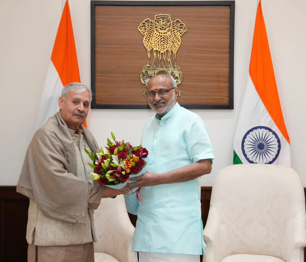 Union Minister Rao Inderjit Singh presenting a floral bouquet to Shri C.P. Radhakrishnan during a formal meeting inside Parliament House with Indian flags in the background.