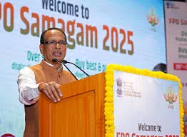 Union Minister Shivraj Singh Chouhan addressing the audience from a podium decorated with yellow marigolds, with a digital backdrop reading 'Welcome to FPO Samagam 2025'.