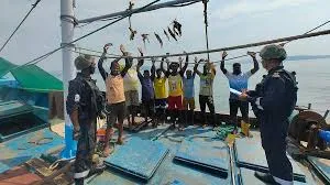 Indian Coast Guard personnel inspecting a fishing boat crew with hands raised during the Sagar Kavach coastal security exercise along the Maharashtra and Goa coast.