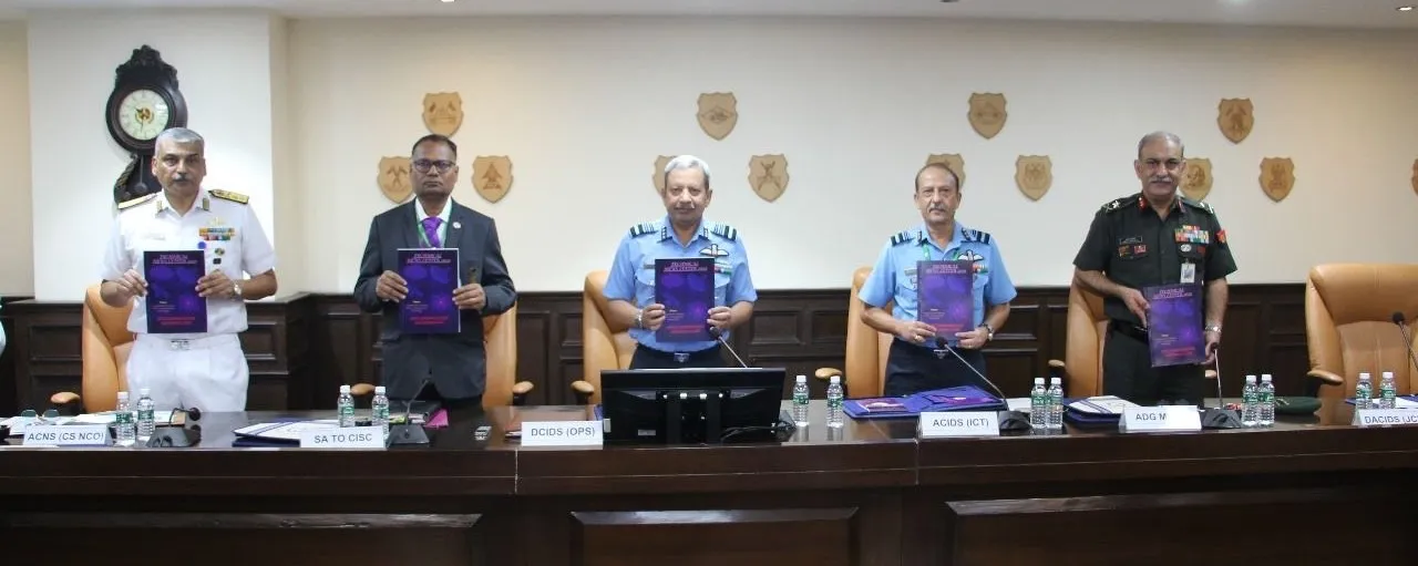 Senior Indian military officials, including Air Marshal Rakesh Sinha, standing at a conference table holding copies of the Technical News Letter 2025 during the JEMB meeting.