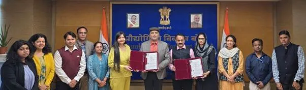 Officials from the Technology Development Board and TechInvention Lifecare holding signed agreement folders for the indigenous PCV-16 vaccine project in front of a blue government backdrop.