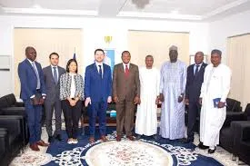 Group photo of the International Monetary Fund delegation led by Julien Reynaud standing with Chadian government officials including the Prime Minister and Finance Minister in a formal office setting in N’Djamena.