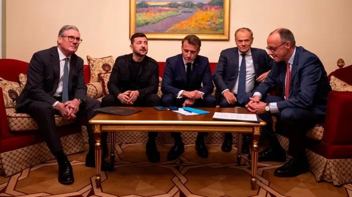 UK Prime Minister Keir Starmer, Ukrainian President Volodymyr Zelenskyy, French President Emmanuel Macron, Polish Prime Minister Donald Tusk, and German Chancellor Friedrich Merz sit together around a coffee table during a diplomatic meeting.
