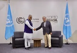Union Minister Bhupender Yadav shaking hands with UN Secretary-General António Guterres in front of a COP30 Brazil backdrop with United Nations flags.