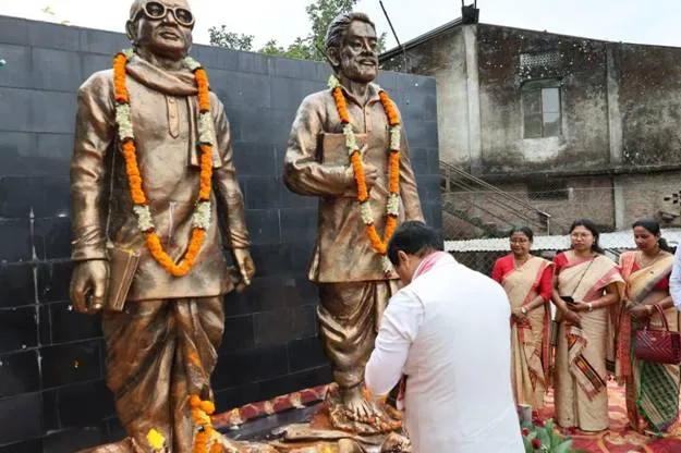 Union Minister Sarbananda Sonowal bowing respectfully before the garlanded bronze statues of tea community leaders during Shramik Kalyan Divas in Dibrugarh, Assam.
