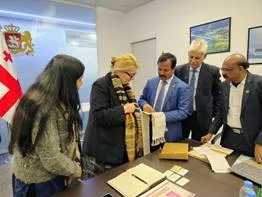 Shri P. Sivakumar of India's Central Silk Board presenting the unique 5-in-1 Silk Stole to a Georgian official during a bilateral meeting in Georgia, with the Georgian flag visible in the background.