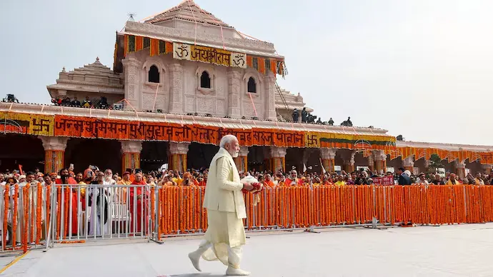 Alternative Text (Alt Text)** | Prime Minister Narendra Modi walks past the flower-decked Shri Ram Janmbhoomi Mandir in Ayodhya, carrying a ritual offering basket during a visit to the temple complex.