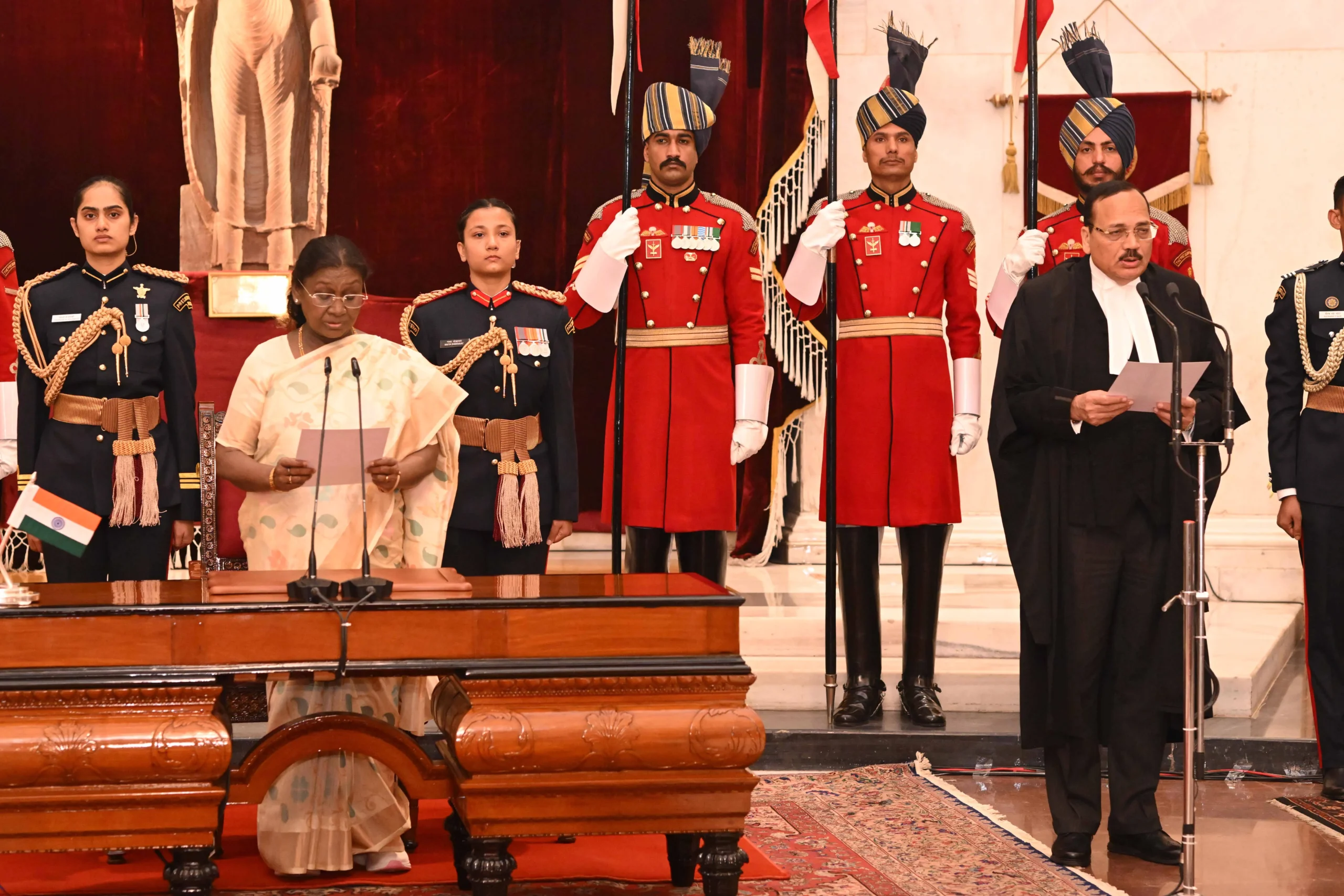 President Droupadi Murmu administers the oath of office to Justice Surya Kant as the Chief Justice of India at the Ganatantra Mandap in Rashtrapati Bhavan, flanked by ceremonial guards in red uniforms.
