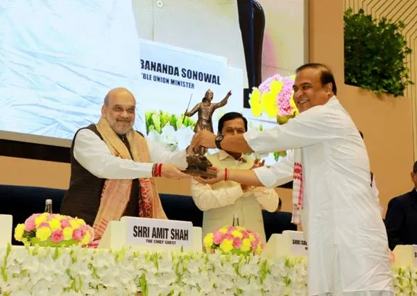 Union Home Minister Amit Shah receives a statue of Ahom General Lachit Barphukan from Assam Chief Minister Himanta Biswa Sarma during a tribute event on stage.