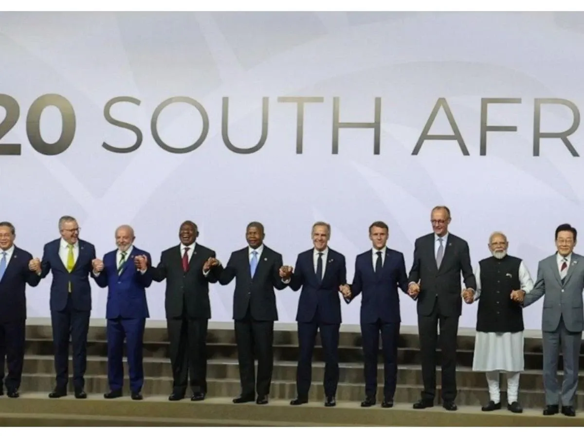 World leaders including Lula da Silva, Cyril Ramaphosa, Emmanuel Macron, and Narendra Modi stand on stage holding hands against a backdrop reading "G20 SOUTH AFRICA" during the summit.