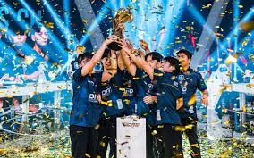 Team Falcons players lifting the golden Esports World Cup trophy on stage surrounded by falling gold confetti and bright spotlights during a championship celebration.