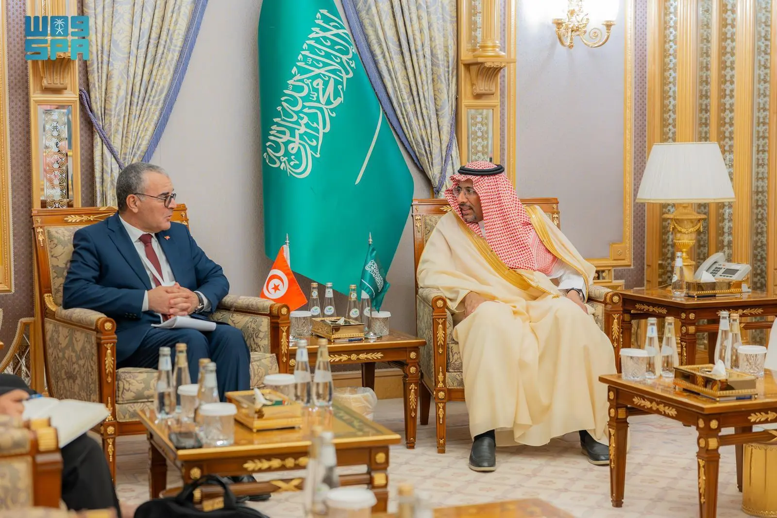 Saudi Minister of Industry Bandar Alkhorayef and Tunisian Minister of Economy Samir Abdelhafid seated in ornate armchairs discussing industrial cooperation in Riyadh, with Saudi and Tunisian flags visible on the side table.