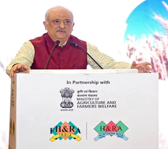 Dr. Devesh Chaturvedi, Secretary of Agriculture, gestures while speaking at a podium displaying Ministry of Agriculture and FHRAI logos during the FPO–Hospitality Summit.