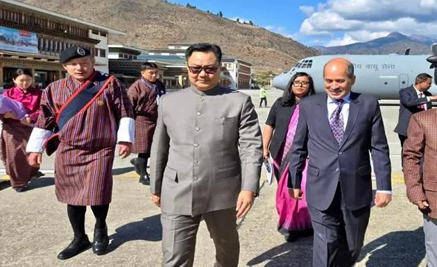 Union Minister Kiren Rijiju walks on the tarmac at Paro Airport in Bhutan alongside officials, with an Indian Air Force aircraft in the background, arriving to retrieve Sacred Buddha Relics.