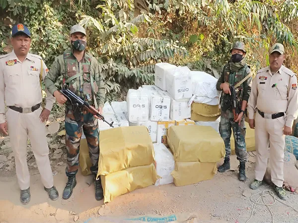 Officials from DRI and security forces standing next to a large pile of seized cartons containing smuggled Oris foreign cigarettes in Mizoram.