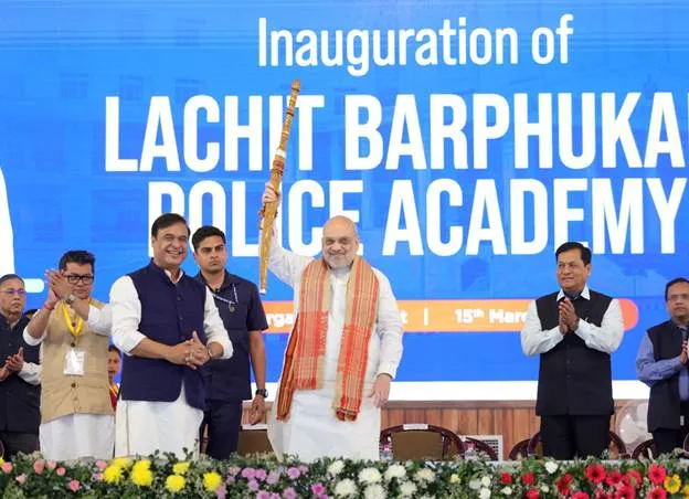 Union Home Minister Amit Shah holds a traditional sword during the inauguration of the Lachit Barphukan Police Academy, standing alongside Assam CM Himanta Biswa Sarma and Union Minister Sarbananda Sonowal.
