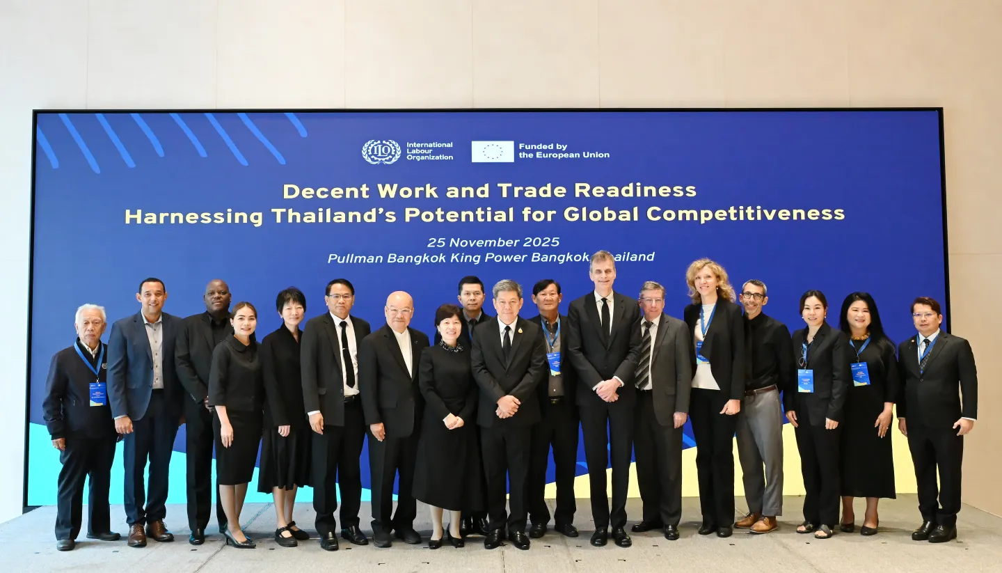 Group photo of over 20 participants at the National Policy Dialogue on Decent Work and Trade Readiness, held on 25 November 2025 at King Power Rangnam in Bangkok, Thailand. The attendees, including representatives from the International Labour Organization, the European Union, the Government of Thailand, workers' and employers' organizations, academia, and civil society, stand in formal attire in front of a large blue backdrop displaying the event title 'Harnessing Thailand’s Potential for Global Competitiveness' along with the ILO and EU logos.